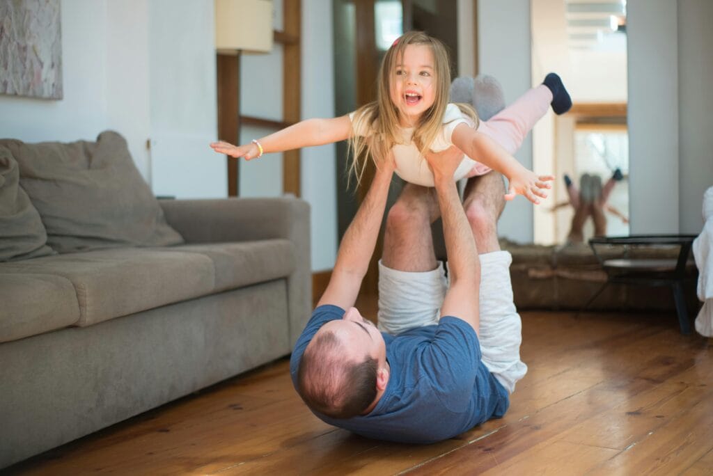 Man lying on the floor while lifting a girl.