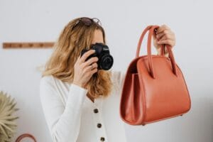 a woman in white long sleeves taking photos-of a handbag