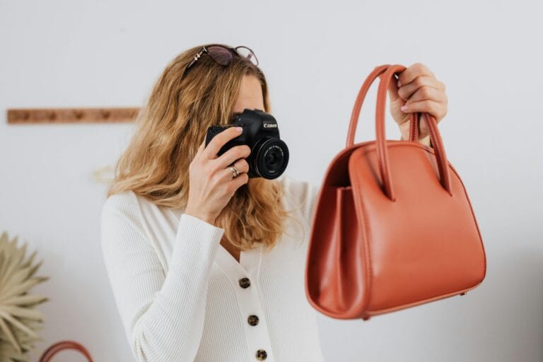 a woman in white long sleeves taking photos-of a handbag