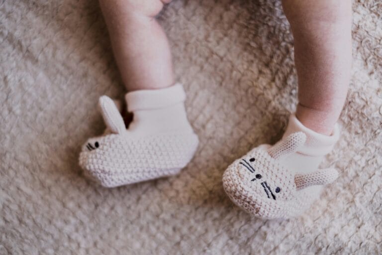 close up photo of knitted footwear of newborn babies