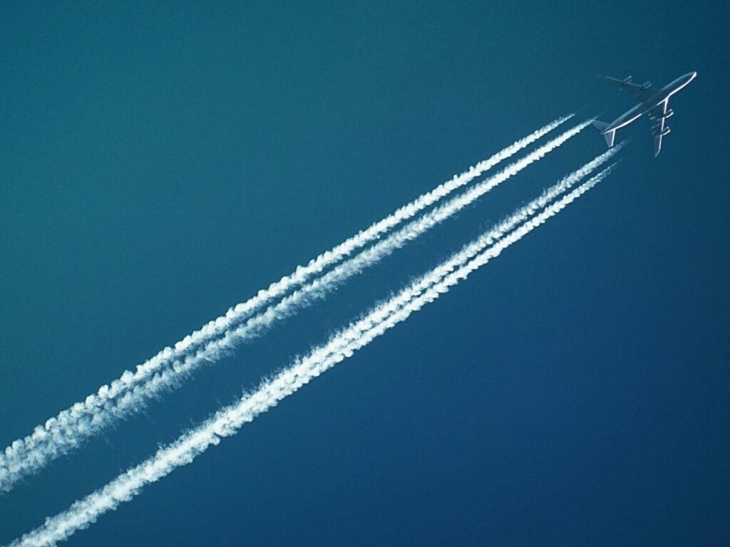 White airplane with smoke under blue sky. How to minimise jet lag after long flights