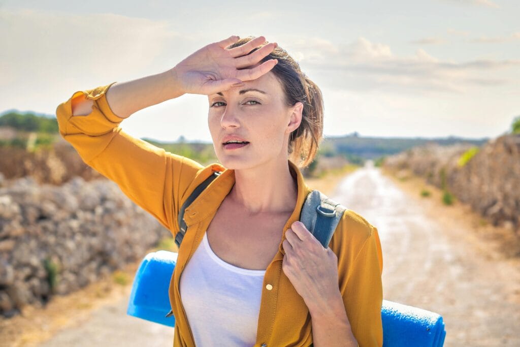 Woman in yellow long sleeve carrying blue yoga mat. Avoid sunstroke while travelling