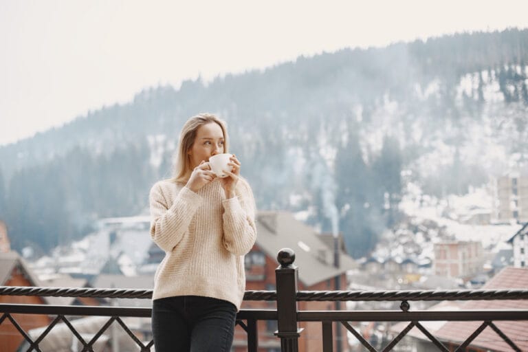 Girl in a warm light coat. Vacation in mountains. Lady with long hair.