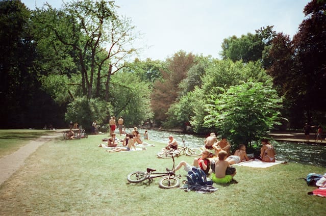 People Relaxing by the River in a Park Setting