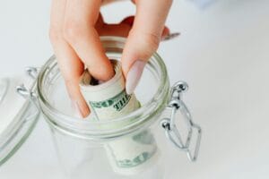Close-Up Shot of a Person Saving Money in the Glass Jar. Emergency cash for solo travellers abroad