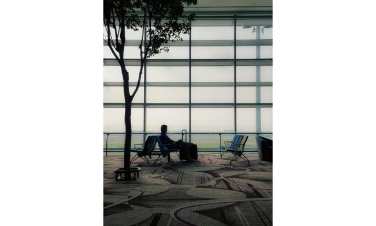 A Man with a Suitcase Sitting Alone at an Airport