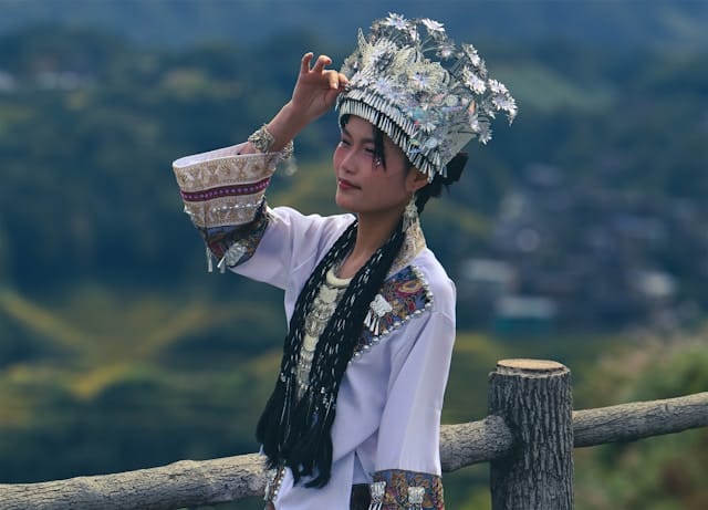 A beautiful Chinese girl wearing a traditional Guanxi dress on Longji rice terraces in Guilin