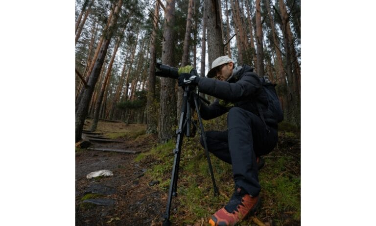Photographer Crouching with Tripod in Forest