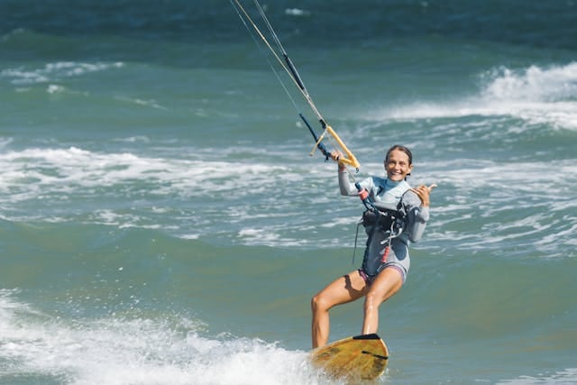 Smiling Woman Kitesurfing and Gesturing