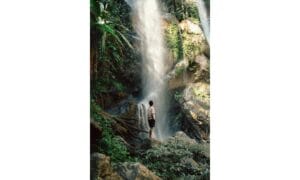 A Man Standing on Big Rock while Looking at the Waterfalls