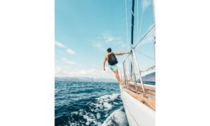 Man Wearing Backpack Standing On Side Of Boat During Daytime