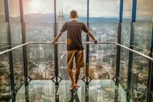 Man in Black T-shirt Looking Out of Glass Windows during Sunset
