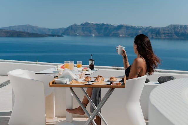 A woman sitting at a table with a view of the ocean