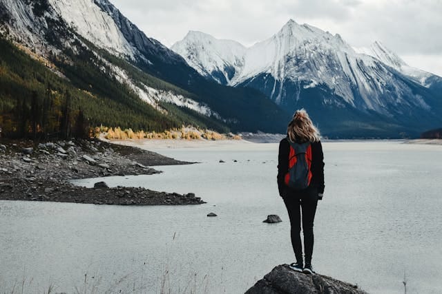 Traveler admiring lake surrounded by snowy mountains
