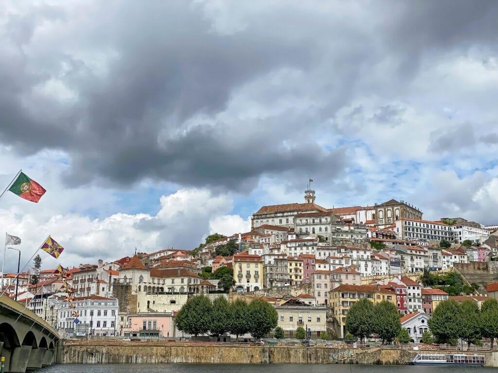The old town of Coimbra with portuguese flag on the bridge over the river Mondego