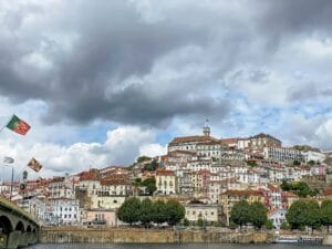 The old town of Coimbra with portuguese flag on the bridge over the river Mondego