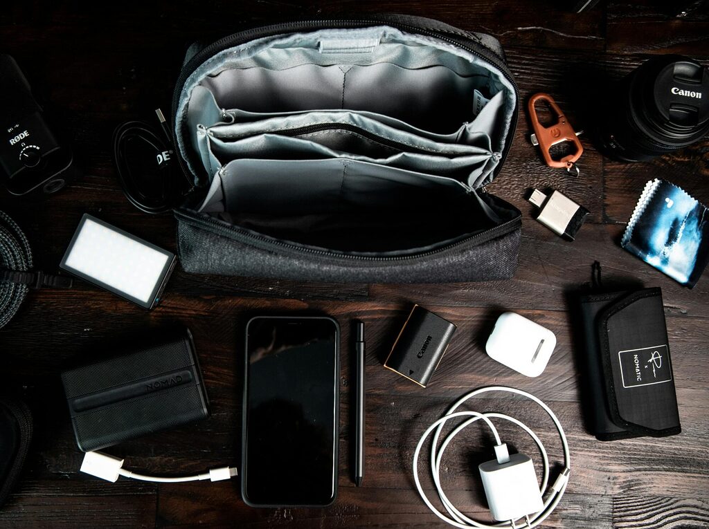 An open electronic travel organiser bag laid flat showing cables, adapters and a power bank neatly arranged in elastic loops and mesh pockets.