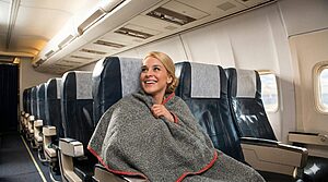Compact travel blankets folded in a carry pouch beside a suitcase showing portability and soft fabric textures for journeys