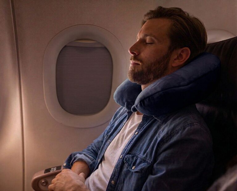 Travel neck pillow resting on an airplane seat with a suitcase nearby showing U-shaped and compact designs for head and neck support