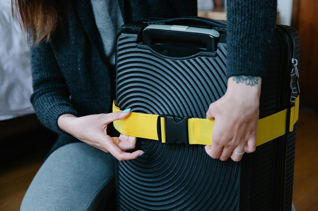 Colourful luggage tags and bright suitcase straps attached to travel bags on an airport baggage carousel
