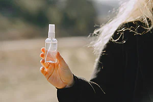 Compact spray bottle for hair placed in a travel toiletry bag showing small size ideal for carry on and daily styling use
