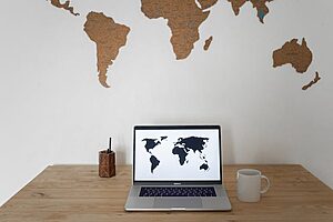 World map on wall and laptop near cup and container