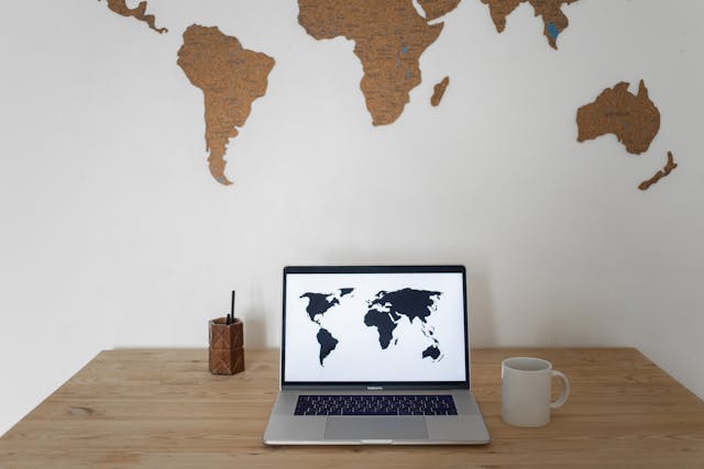 World map on wall and laptop near cup and container