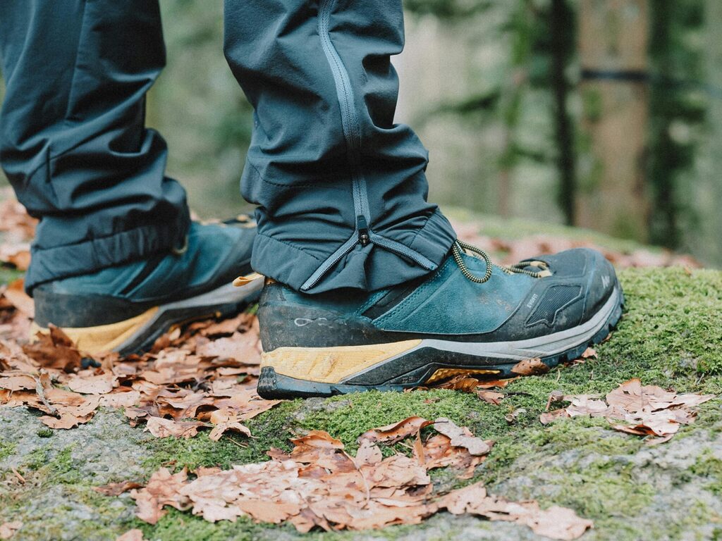 Hiker wearing ankle mid and knee hiking gaiters showing protection from mud water and snow on mountain trail