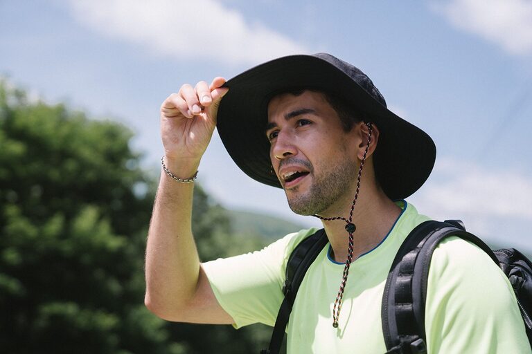 Hiker wearing a wide-brim hiking hat on a sunny mountain trail