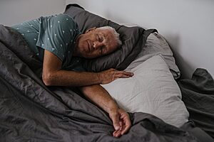 Elderly man resting comfortably in bed, adjusting sleep his time to prepare jet lag in a long haul flight.