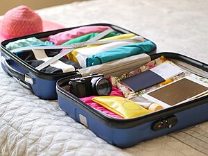 Open suitcase with camera, clothes and passport