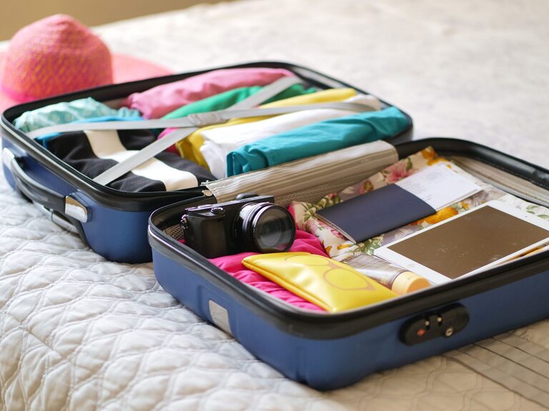 Open suitcase with camera, clothes and passport