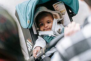 Cute baby in a stroller with parents for outdoor stroll