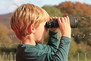 Young child using binoculars during a nature holiday