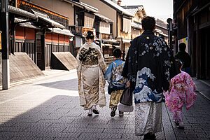A family in colourful kimonos walking through a historic street in Kyoto, Japan.