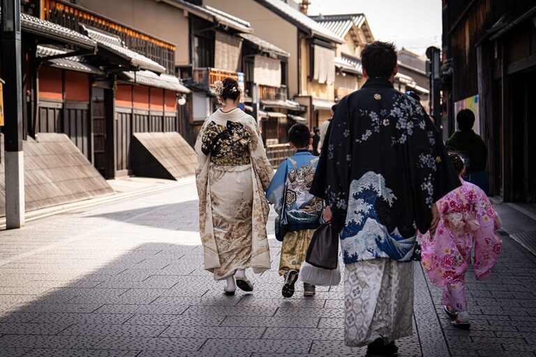 A family in colourful kimonos walking through a historic street in Kyoto, Japan.