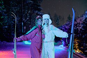 Teens enjoy night skiing under vibrant neon lights, showcasing stylish winter fashion.