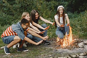 Group of teenagers enjoying a warm campfire during a camping trip in the outdoors.