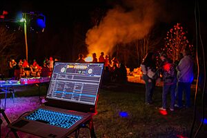 Vibrant outdoor festival night party scene featuring a DJ setup and blazing bonfire