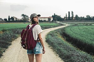 Young traveller with backpack walks through a scenic rural landscape