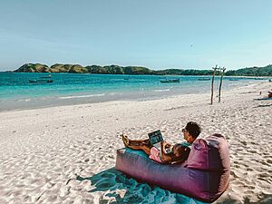Digital nomad working remotely on the beach while travelling