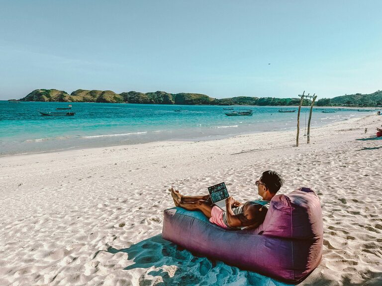Digital nomad working remotely on the beach while travelling
