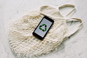 An eco-friendly message displayed on a smartphone resting on a reusable mesh bag, symbolising sustainability.